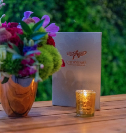 Menu, flower vase and lit candle in the outdoor Wine Garden private dining space